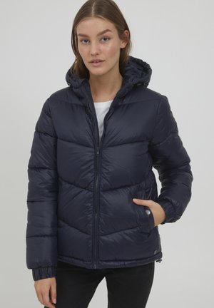 Giacca puffer blu navy con cappuccio, caratterizzata da segmenti trapuntati, zip frontale e polsini elasticizzati. Tessuto sintetico liscio e lucido.
