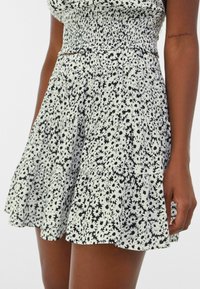 Black and white floral dress with a smocked bodice, tiered ruffle hem, short length, and a soft fabric texture.