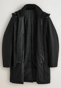 Chaqueta exterior negra con un forro interior acolchado, que presenta un cuello alto, cierre de cremallera y botones a presión. Textura suave y longitud media.