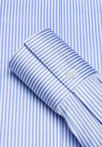 Camicia a righe azzurro chiaro e bianca con polsini a bottone, realizzata in tessuto morbido. Presenta righe sottili alternate e cuciture ben rifinite.