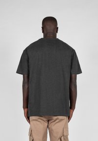 Tricou din bumbac gri cărbune, mâneci scurte, guler rotund, croială confortabilă, textură netedă, fără logo-uri sau grafice vizibile pe spate.