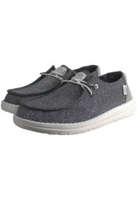 Scarpe slip-on argento glitter con punta arrotondata, suola in gomma bianca e lacci grigi chiari. Branding sulla linguetta e sul lato. Texture morbida.