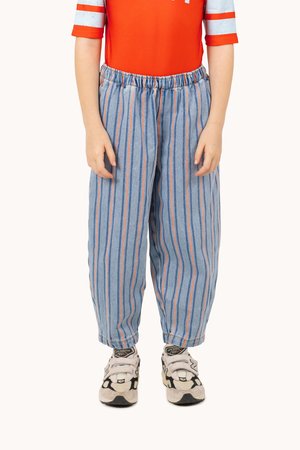Gestreifte blaue Denim-Hosen mit orangefarbenen und blauen vertikalen Linien, elastischem Bund, lockerer Passform, kombiniert mit klobigen Sneakers.