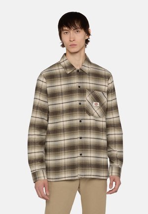 Camisa de franela a cuadros marrón y crema con botones en la parte delantera, un bolsillo en el pecho y botones negros. Tejido suave con un ajuste relajado.