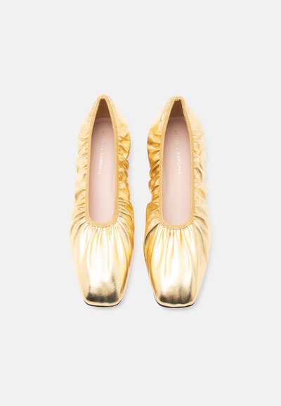 Ζευγάρι μεταλλικά χρυσά μπαλέτα από δέρμα με ρυτιδώσεις και τετράγωνα μύτη, απεικονισμένα από ψηλά σε λευκό φόντο.