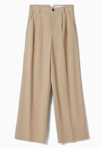 Beżowe spodnie o szerokich nogawkach wykonane z lekkiego materiału, z przodu z pliskami, z zapięciem na guzik oraz kieszeniami po bokach. Gładka faktura.
