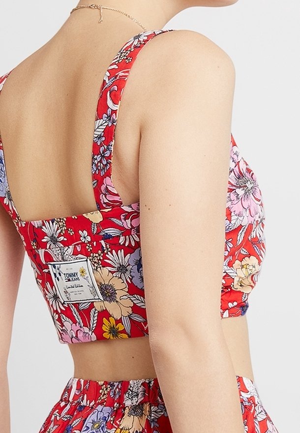 Top court à fleurs rouges avec larges bretelles, doté d'un dos carré, en tissu coton, avec une étiquette latérale portant le logo de la marque.