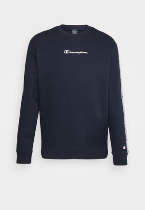 Granatowa bluza Champion z białym logo na piersi, wzorzyste paski z logo na rękawach oraz ściągaczami przy mankietach i u dołu.