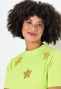 Grøn t-shirt med tre gyldne stjerneapplikationer, lavet af glat stof med en let blank finish og korte ærmer.
