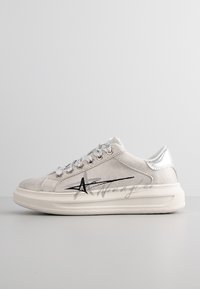 Ljusgrå mockaskor med silverdetaljer, rund form, snörning och grafisk design på sidan. Platt gummisula.