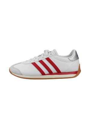 Zapatilla deportiva baja blanca con rayas rojas, suela de goma y detalle plateado en el talón, mostrada en perfil lateral mirando hacia la derecha.