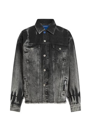 Jaqueta de denim preto e cinza com um padrão desbotado, dois bolsos no peito, botões de pressão e uma barra desfiada. Apresenta uma etiqueta na lateral.