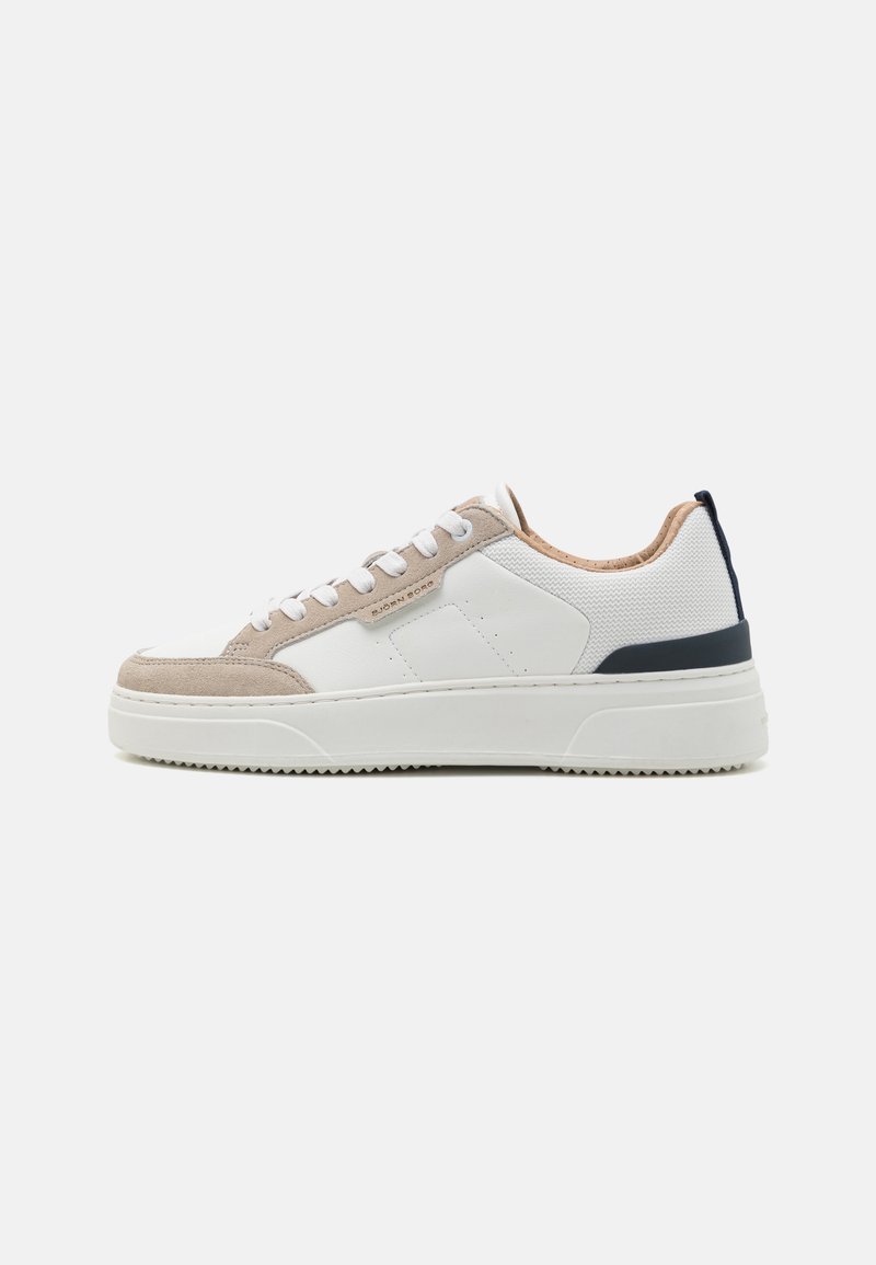 Heren sneaker met een wit mesh bovenwerk, beige suede accenten, marineblauwe hiel detail en een gestructureerde witte rubberen zool. Laag uitgesneden ontwerp.