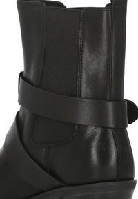 Stivale nero alla caviglia in pelle liscia, con punta arrotondata e una larga fascia intorno al collo del piede per un maggiore contrasto di design.