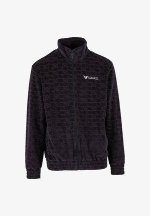 Must sõmerdunud musta vetthülgava jakiga, millel on kõrge krae, elastsed mansetid ja "Colucci" logo vasakul rinnal.