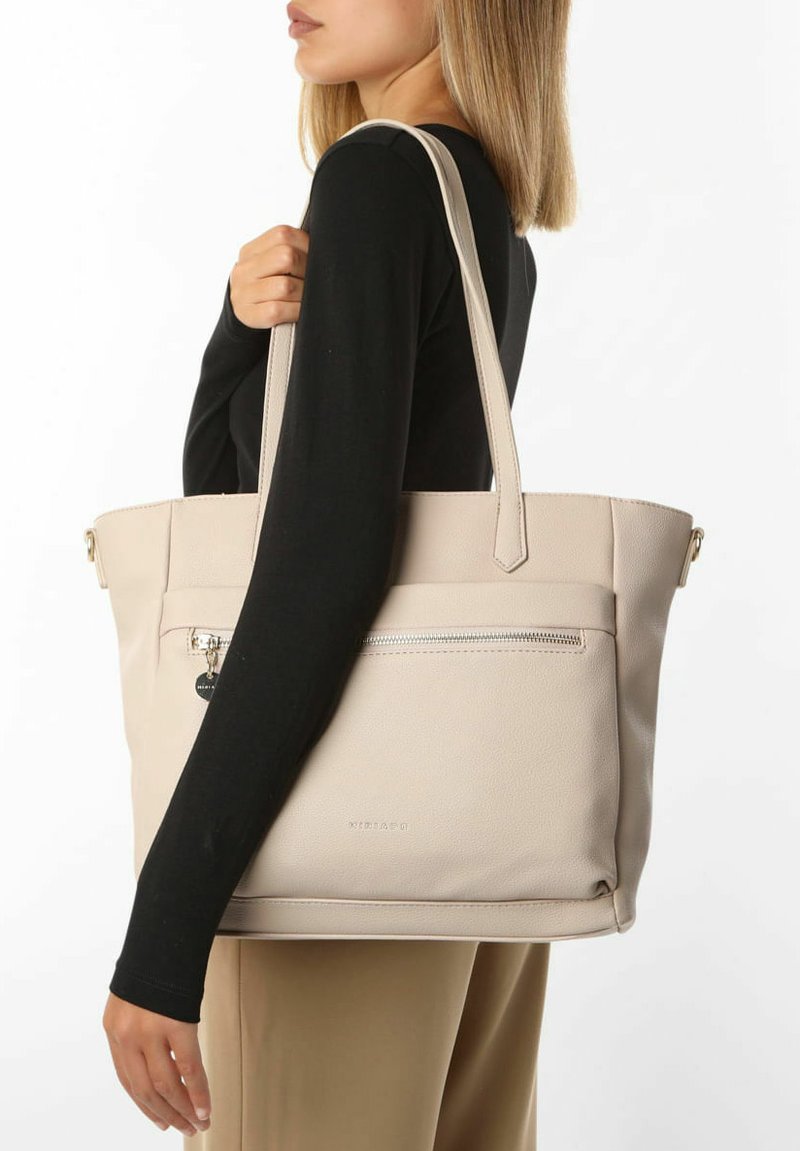 Beige faux læder tote taske med dobbelt håndtag, lynlåslomme og glat tekstur. Har et logo på forsiden og elegant syning.