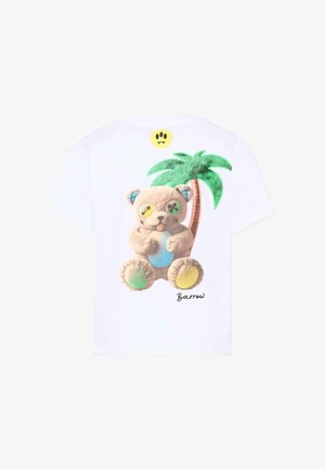 Wit T-shirt met een kleurrijke teddybeer met ongelijk geknoopte oogknopen, zittend voor een groene palmboom, gesigneerd met "Barrow".