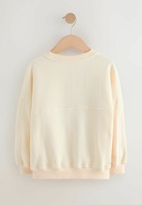 Cream-colored sweatshirt with a relaxed fit, ribbed collar, and cuffs. Features a smooth texture and a seam detail across the back.