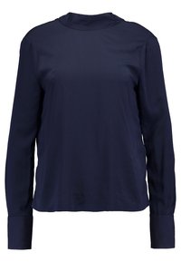 Blouse bleu marine à manches longues avec col montant et poignets boutonnés, en tissu lisse, présentée sur fond blanc.