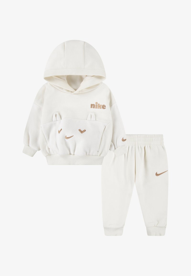 Dvojdielny detský outfit pozostávajúci z krémovej mikiny s ušami medveďa a klokankou, a zladených teplákov s logom.