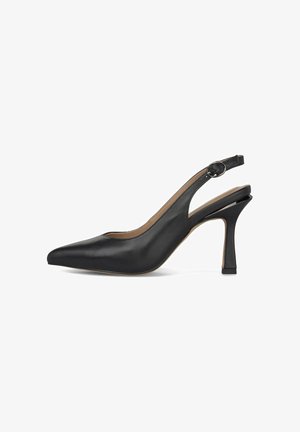 Zapato de tacón alto de cuero negro con puntera puntiaguda y correa con hebilla redonda, tacón delgado y cónico sobre fondo blanco.