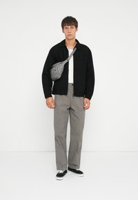 Black button-up shirt, white t-shirt, gray checkered pants, and black sneakers. Gray crossbody bag worn over the left shoulder.