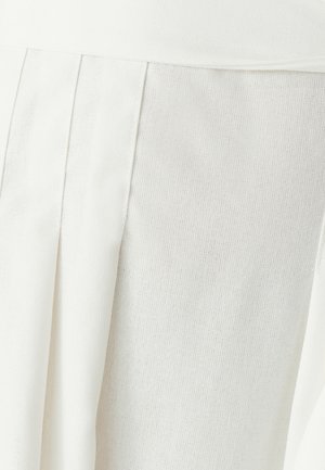 Hvid nederdel med plisseringer, lavet af tekstureret stof. Har et glat taljebånd og et blødt, vævet mønster i hele materialet.