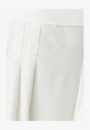 Hvid nederdel med plisseringer, lavet af tekstureret stof. Har et glat taljebånd og et blødt, vævet mønster i hele materialet.