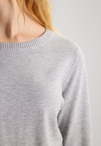 Maglione grigio chiaro a maniche lunghe con collo a coste, texture morbida e dettagli di cucitura minimi.