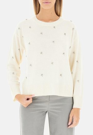 Maglione a maglia crema con orlo a coste, caratterizzato da decorazioni in argento sparse. Maniche lunghe con vestibilità comoda.