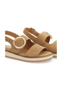 Sandales en daim beige avec une large bride, un accent circulaire et une bride arrière. Caractérisées par une semelle intermédiaire de couleur claire et une semelle extérieure brun texturé.