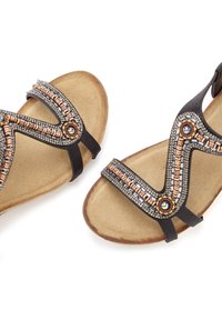 Schwarze Sandalen mit einem dekorativen Bead-Design in Gold, Kupfer und Silber, ausgestattet mit einer gepolsterten, braunen Fußbett und eleganten Riemen.