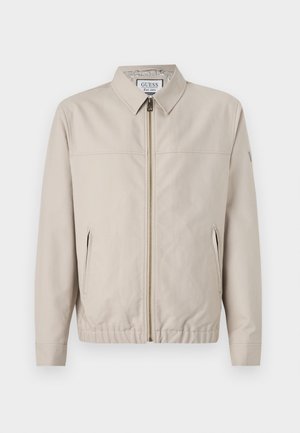 Chaqueta ligera beige con cierre de cremallera en el frente, diseño con cuello, dos bolsillos laterales y puños elásticos. Textura suave con un detalle mínimo.