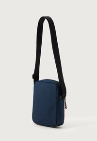 Borsa a tracolla blu navy realizzata in tessuto resistente, con una forma rettangolare piatta, tracolla nera regolabile e chiusura con zip.