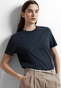 Marineblauwe T-shirt met korte mouwen, gemaakt van katoen, met een ronde hals en een gladde textuur, gecombineerd met lichtbeige hoge taillebroeken.
