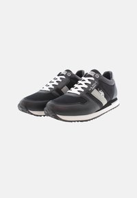 Sneaker sportive nere realizzate con una combinazione di pelle sintetica e mesh. Presentano lacci bianchi, dettagli con strisce argentate e suole in gomma testurizzata.