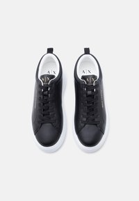 Ζευγάρι μαύρα δερμάτινα αθλητικά παπούτσια με λευκές σόλες, μαύρα κορδόνια και λογότυπο Armani Exchange σε χρυσό στα πλαϊνά και στη γλώσσα.