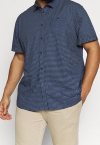 Kortermelig overhemd met knopen in marineblauw met een wit geometrisch patroon. Gemaakt van lichtgewicht stof met een gestructureerde kraag en borstzak.
