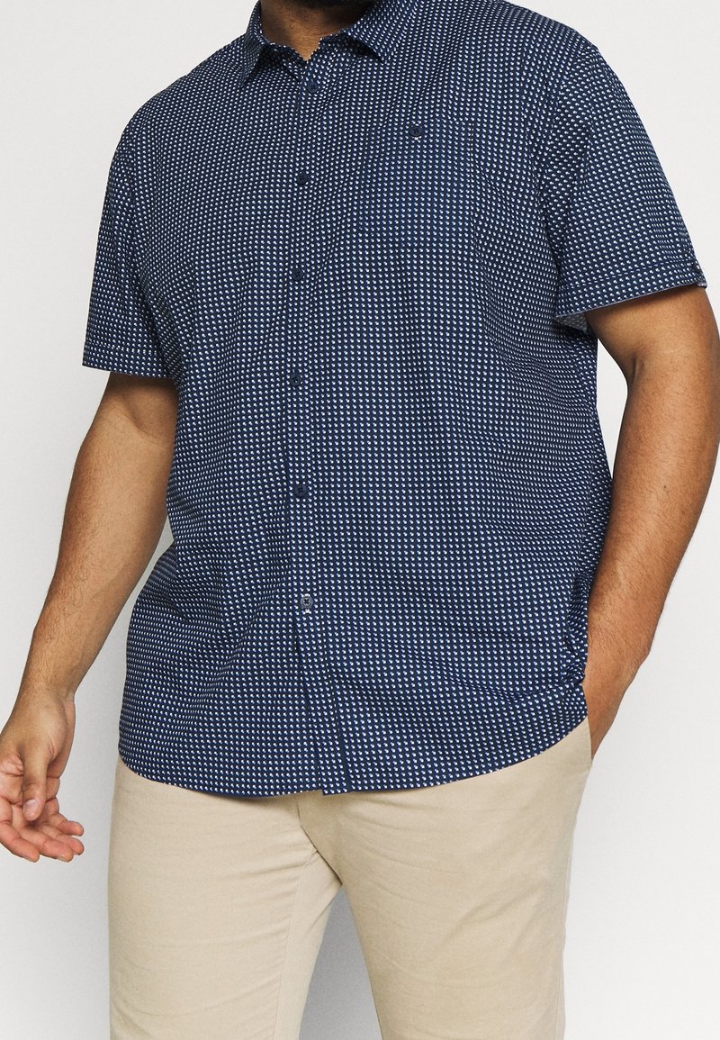 Kortermelig overhemd met knopen in marineblauw met een wit geometrisch patroon. Gemaakt van lichtgewicht stof met een gestructureerde kraag en borstzak.