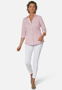 Helles rosa, knöpfbares Hemd mit Kragen und Dreiviertelärmeln, kombiniert mit weißen Slim-Fit-Hosen und beigen Slippers.