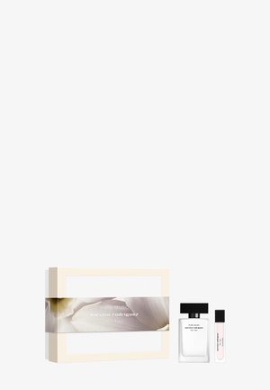 Caja de regalo blanca y beige con un diseño floral, que contiene un frasco de perfume transparente con tapa negra y un vial más pequeño.