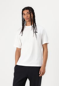 White short-sleeve t-shirt made of cotton, featuring a small black North Face logo on the left chest, with a round neckline and a relaxed fit.