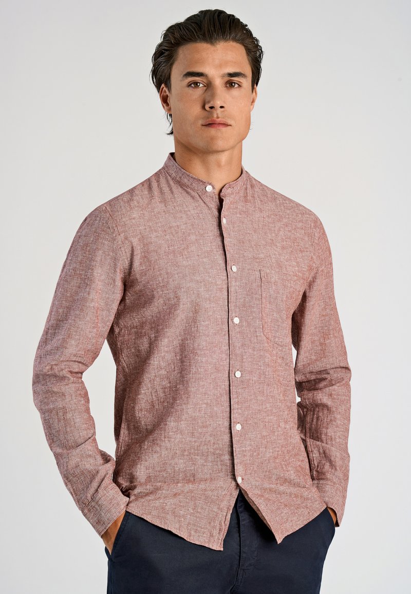 Camicia rossa a fantasia con colletto alla coreana, dotata di taschino sul petto e maniche lunghe, indossata da un modello su uno sfondo chiaro.
