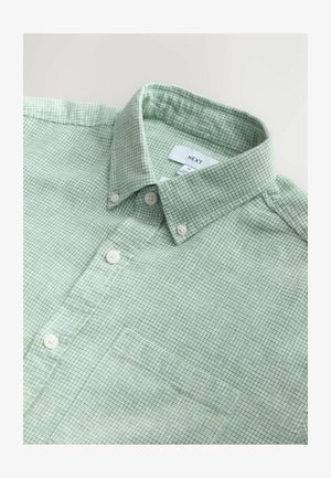 Vihreä ruudullinen paitapusero, jossa on klassinen kaulus, valkoiset napit ja etutasku. Valmistettu kevyestä, teksturoidusta kankaasta.