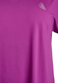 Short-sleeve, v-neck t-shirt in bright purple fabric. Features a textured pattern and a small white logo on the upper right. Soft, stretchy material.