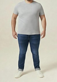Grå kortärmad t-shirt i kombination med mörkblå slim-fit jeans och vita sneakers. Avslappnad outfit med en enkel design och klassiska färger.