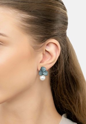 Orecchini a forma di fiore blu con decorazioni in cristallo e una goccia di perla. Presentano dettagli intricati e una finitura metallica.