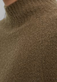 Khaki gestructureerde turtleneck trui met een geribde halslijn, gemaakt van een zacht, pluizig materiaal, met een gezellige uitstraling.