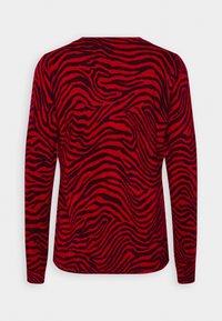 Pull rouge à manches longues avec un motif de vagues noires et rayures zébrées en zigzag, poignets côtelés et texture lisse.