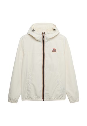 Chaqueta ligera de crema con capucha, cremallera negra, acentos a rayas en contraste y logotipo en el pecho. Cuenta con puños y dobladillo elásticos.